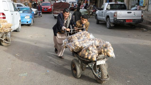 يمنيان يدفعان عربة محملة بأطعمة