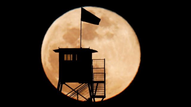 A ranger's tower is silhouetted over a Supermoon near Ruhama in south Israel