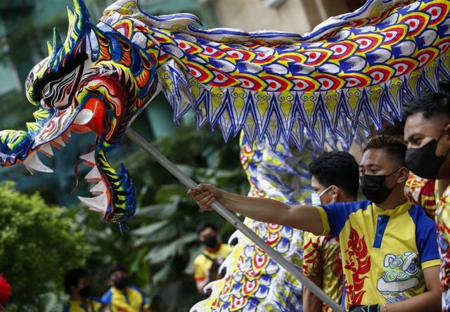 农历新年前夕，在菲律宾马尼拉大都会奎松市，舞龙者在商业购物中心表演时摆姿势拍照留念。