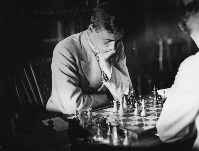 1933 ஆகஸ்ட் 1 ஆம் தேதி எடுக்கப்பட்ட இந்தப் புகைப்படத்தில், சசெக்ஸின் ஹேஸ்டிங்ஸில் நடந்த பிரிட்டிஷ் செஸ் சாம்பியன்ஷிப்பின் போது சுல்தான் கான் CHOD அலெக்சாண்டருக்கு எதிராக விளையாடுகிறார்.