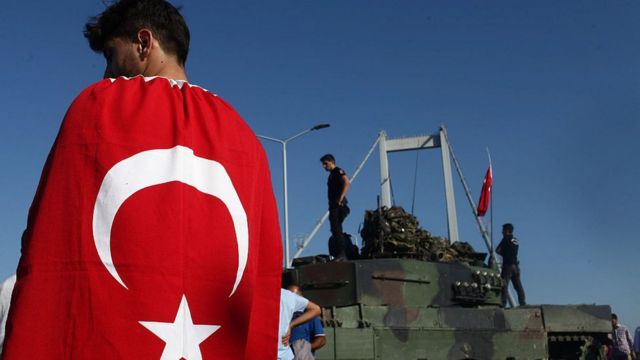 Un joven con una bandera turca pasa frente a uno de los tanques empleados en el fallido intento de golpe de Estado de julio de 2016