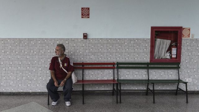 Un señor sentado en un banco en un colegio electoral de Caracas-