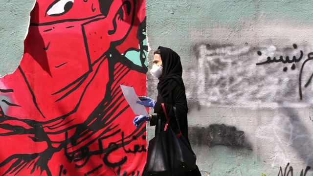 Una mujer camina delante de un grafiti en Teherán, Irán.