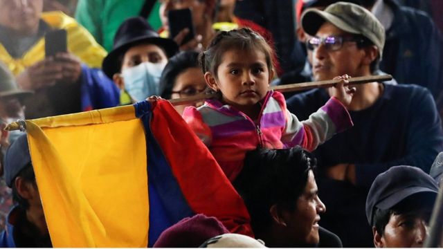 A girl with a flag of Ecuador with other people.