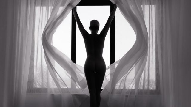 Mujer de espaldas y en silueta contra una ventana