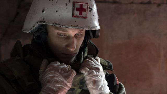 Denys in a white helmet with a red cross.  The atmosphere is gloomy and he looks pensive.