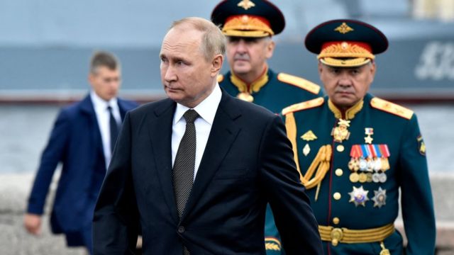 Russia's President Vladimir Putin (L), flanked by Russia's Defence Minister Sergei Shoigu (R), walks as he takes part in the main naval parade marking the Russian Navy Day, in St. Petersburg on July 31, 2022.