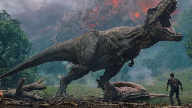 Cena do filme Jurassic Park: Reino Ameaçado, em que um enorme dinossauro ruge obervado pelo personagem principal, com cenas de um vulcão em erupção no fundo