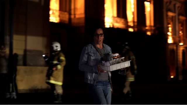 Pesquisadora tenta resgatar objetos de pesquisa do meus em meio a chamas