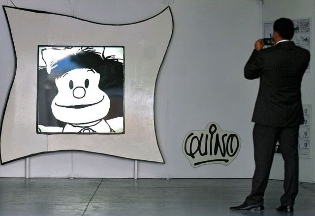 A man photographs a caricature of Mafalda.