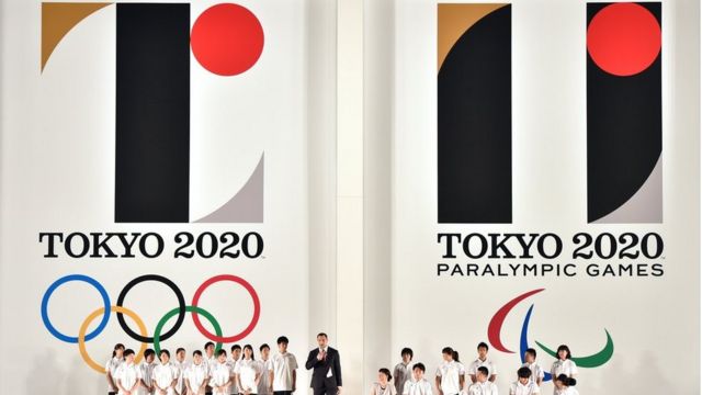 Hammer throw gold medalist Koji Murofushi (C), accompanied by young athletes, delivers a speech as the logo marks of the Tokyo 2020 Olympic (L) and Paralympic (R) Games are unveiled at the Tokyo city hall on July 24, 2015.