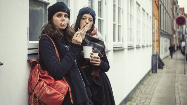 Две женщины курят и пьют кофе