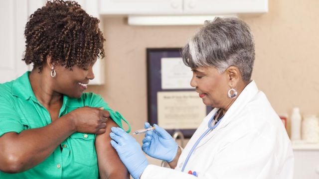 Enfermeira dá vacina em uma mulher