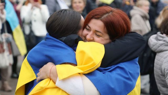 Dua wanita yang mengibarkan bendera Ukraina saling berpelukan di Odessa.