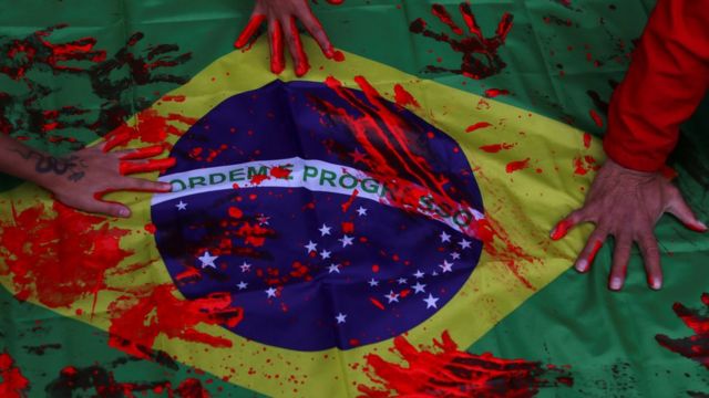 Des militants du mouvement noir posent leurs mains, recouvertes de peinture rouge, sur un drapeau brésilien, lors d'une manifestation contre le racisme et la violence policière à Sao Paulo.