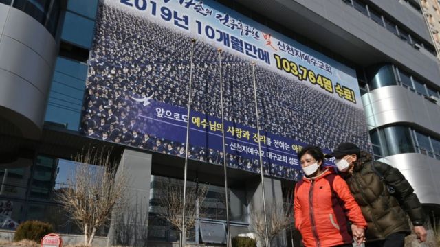 Pedestrians wearing face masks walk in front of the Daegu branch of the Shincheonji Church