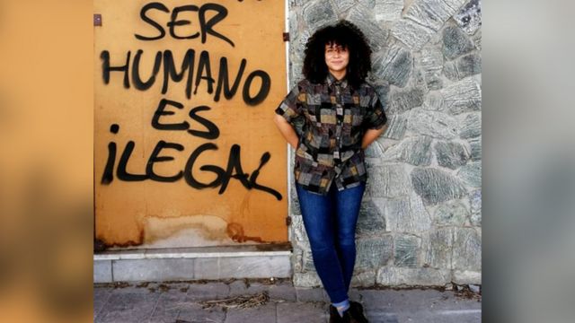 Jai en España, con un letrero que dice "Ser humano es ilegal"