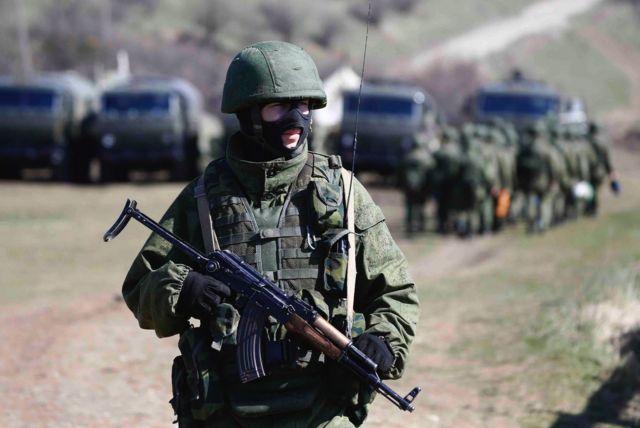 An armed man, believed to be a Russian soldier, stands on guard outside a military base in Perevalnoye, near the Crimean city of Simferopol on 21 March 2014