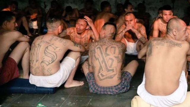 Detentos sentados no chão em prisão em El Salvador
