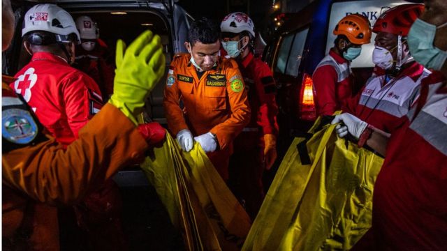 Indonesian search and rescue and red cross personnel carry a body bag to ambulance as they recovered for victims and fuselage of the Lion Air flight JT 610 at Tanjung Priok port on November 3, 2018