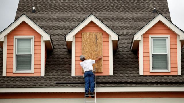 Un hombre coloca una protección de madera en la ventana de su casa en Carolina del Sur.