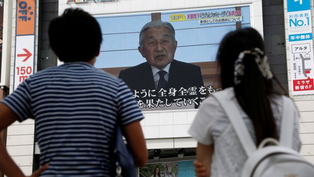 Japoneses observam a mensagem do imperador em telas nas ruas