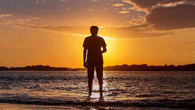 La silueta de un hombre observando el sol poniente