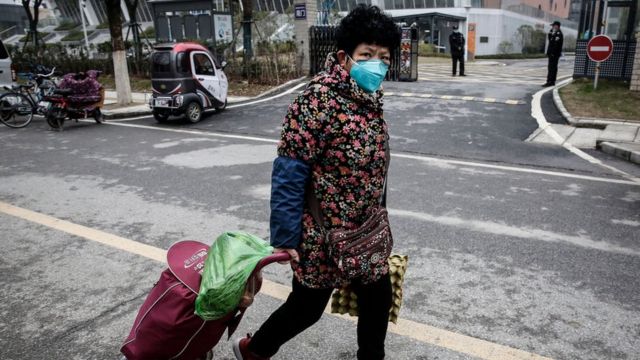 Una mujer usa una mascarilla mientras camina por la calle en Wuhan.