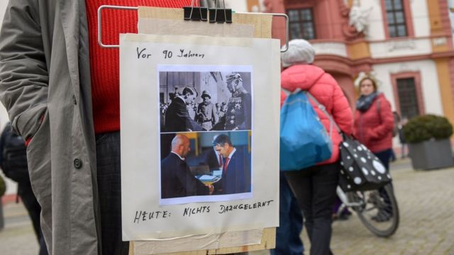 Ein Demonstrant in Deutschland trägt ein Plakat, das die Ereignisse in Thüringen mit dem Aufstieg Adolf Hitlers vergleicht.