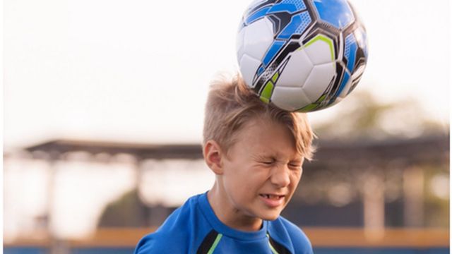 Menino cabeceando a bola