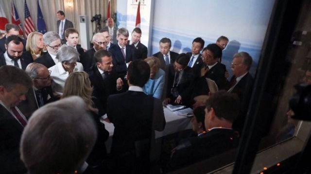G7 leaders gather in a tight crowd around a narrow table