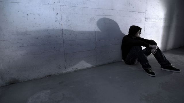 Adolescente sentado em muro