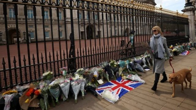 A mourner brings flowers to Buckingham Palace