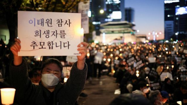 A woman holds up a memorial sign at a candlelight vigil commemorating the Itaewon stampede in Seoul Plaza (5/11/2022)