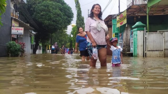 Seorang ibu dan anak melewati banjir di Jakarta Selatan, Selasa (25/02).