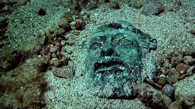 Cara de una estatua griega en la arena