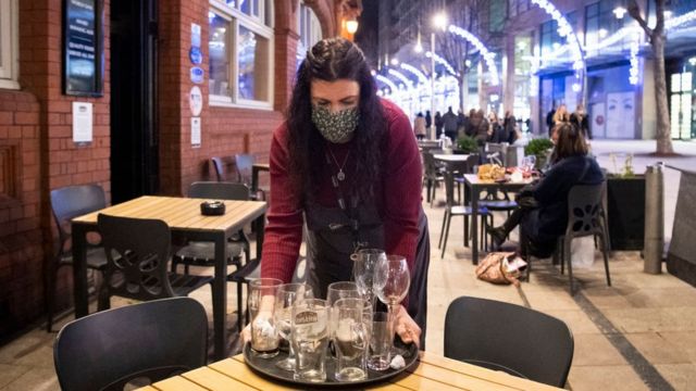 A woman holds cups at a bar in Cardiff, Wales