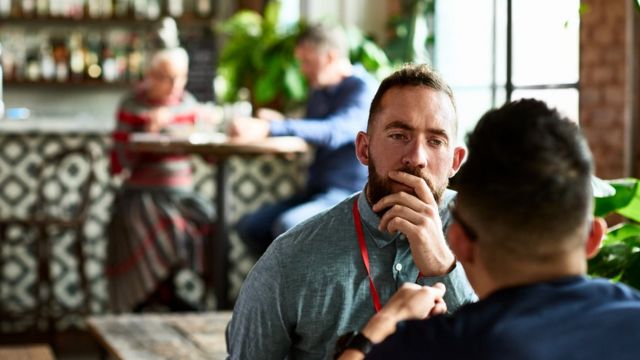 Hombres conversan en un café.