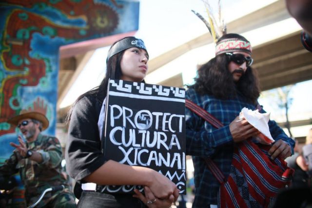 A woman holds up a sign calling for the protection of Chicano culture in Chicano Park, San Diego.