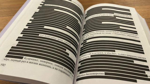 Un libro abierto con franjas negras que oscurecen la mayoría de las líneas de texto