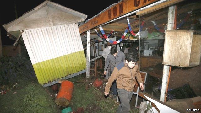 People recover items from a destroyed shop