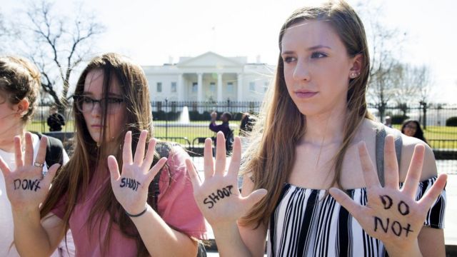 ホワイトハウスの前で、「撃たないで」と手に書き抗議する若者たち
