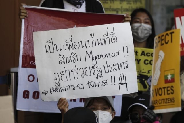 A demonstrator holds a placard reading "A good neighbour will not support a military coup" during a protest against the Myanmar military coup, outside the Embassy of Thailand in Yangon, Myanmar, 24 February 2021.