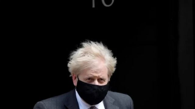 Boris Johnson de máscara, em frente a fundo preto