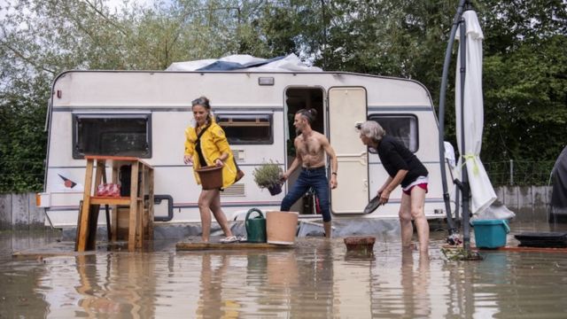 People try to retrieve their belongings in a caravan from a flooded camp in Outenbach, Switzerland