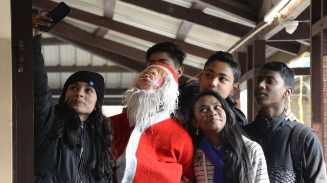 Pas de Noël sans selfie, en Inde, des jeunes se prennent en photo avec le Père noël dans une église catholique.