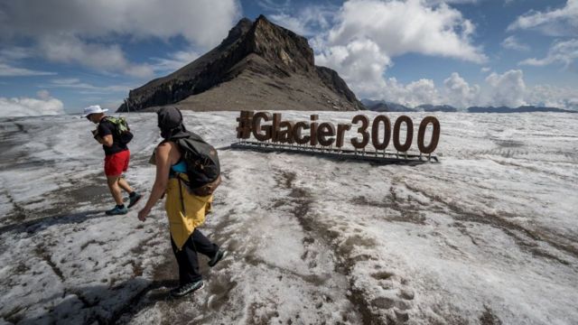 Turistas caminando junto a una señal del Glaciar 3000 en el Glaciar Tsanfleuron por encima de Les Diablerets, Suiza. el 6 de agosto de 2022