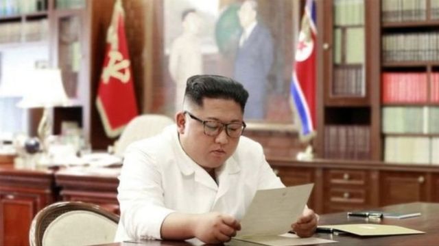 Kim Jong-un wa Koreya ya ruguru ubwo yarimo asoma ibaruwa yohererejwe na Perezida Donald Trump w'Amerika