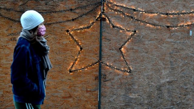 A woman in a face mask passes a Christmas decoration in Berlin, 16 December 2020