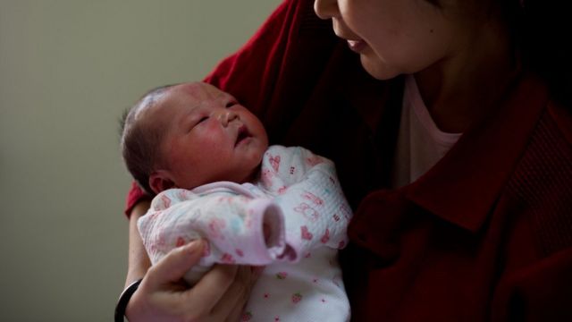 Peking'de bir kadın bebeğini kucaklıyor